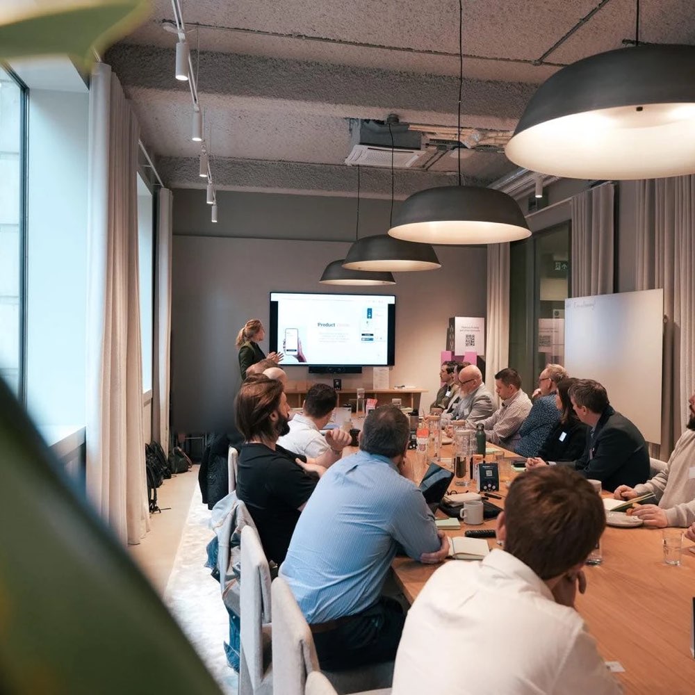 An Acquired team member presenting to guests seated around a long meeting table